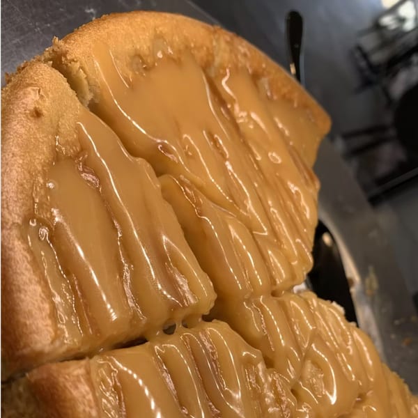 Close-up of a golden-brown cake or pastry generously topped with a thick, glossy caramel sauce.