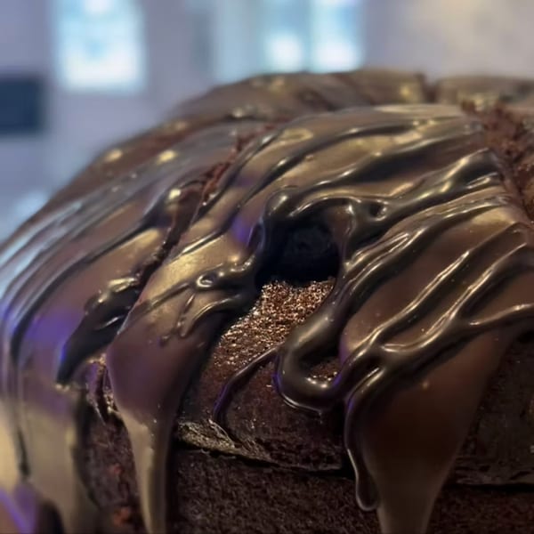 Close-up of a rich chocolate cake with glossy chocolate ganache drizzled over the top.
