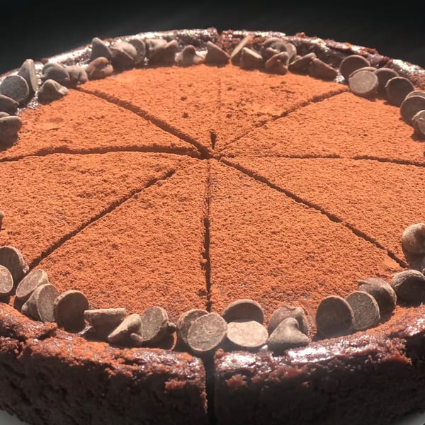 A chocolate cake from How Delish HD, dusted with cocoa powder and garnished with chocolate chips.