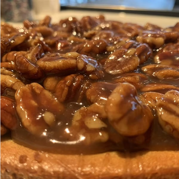Close-up of a pecan pie with a glistening, rich caramel topping and whole pecans.