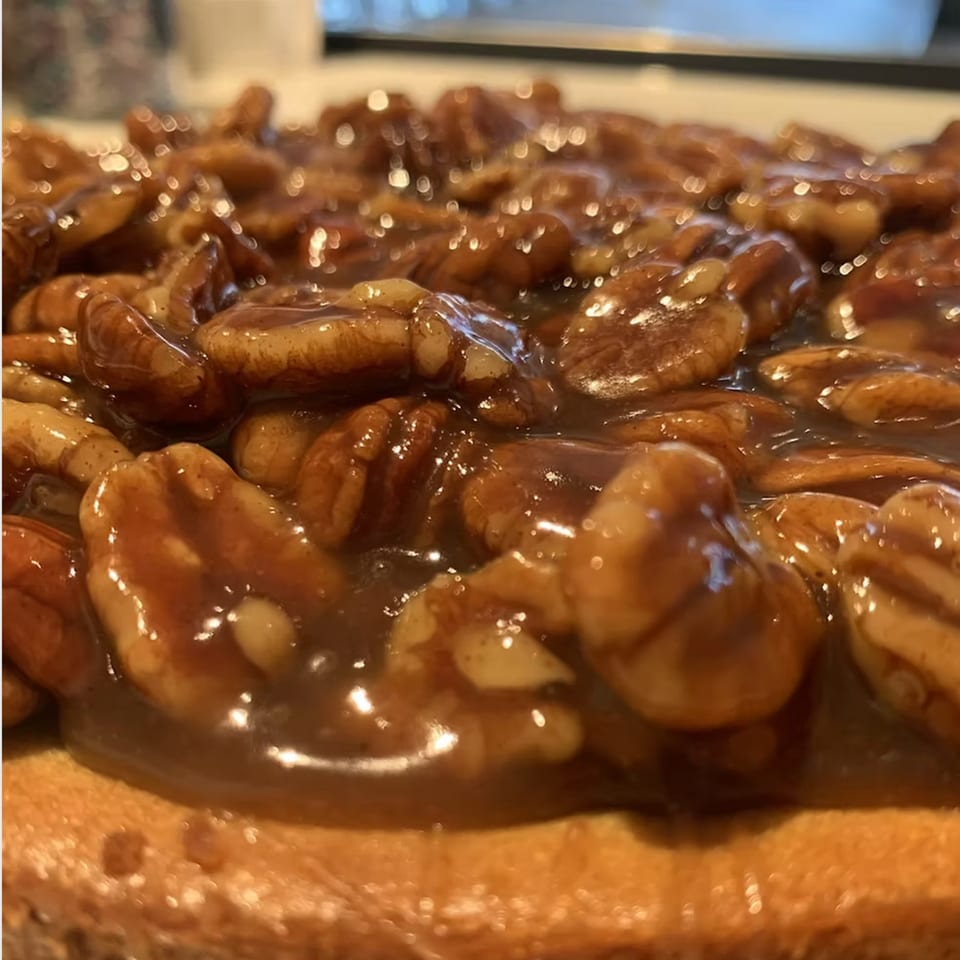 Close-up of a pecan pie with a glistening, rich caramel topping and whole pecans.