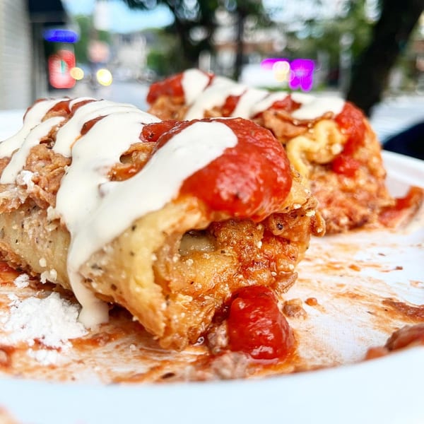 Close-up of fried food with white sauce and red tomato sauce on a white plate.